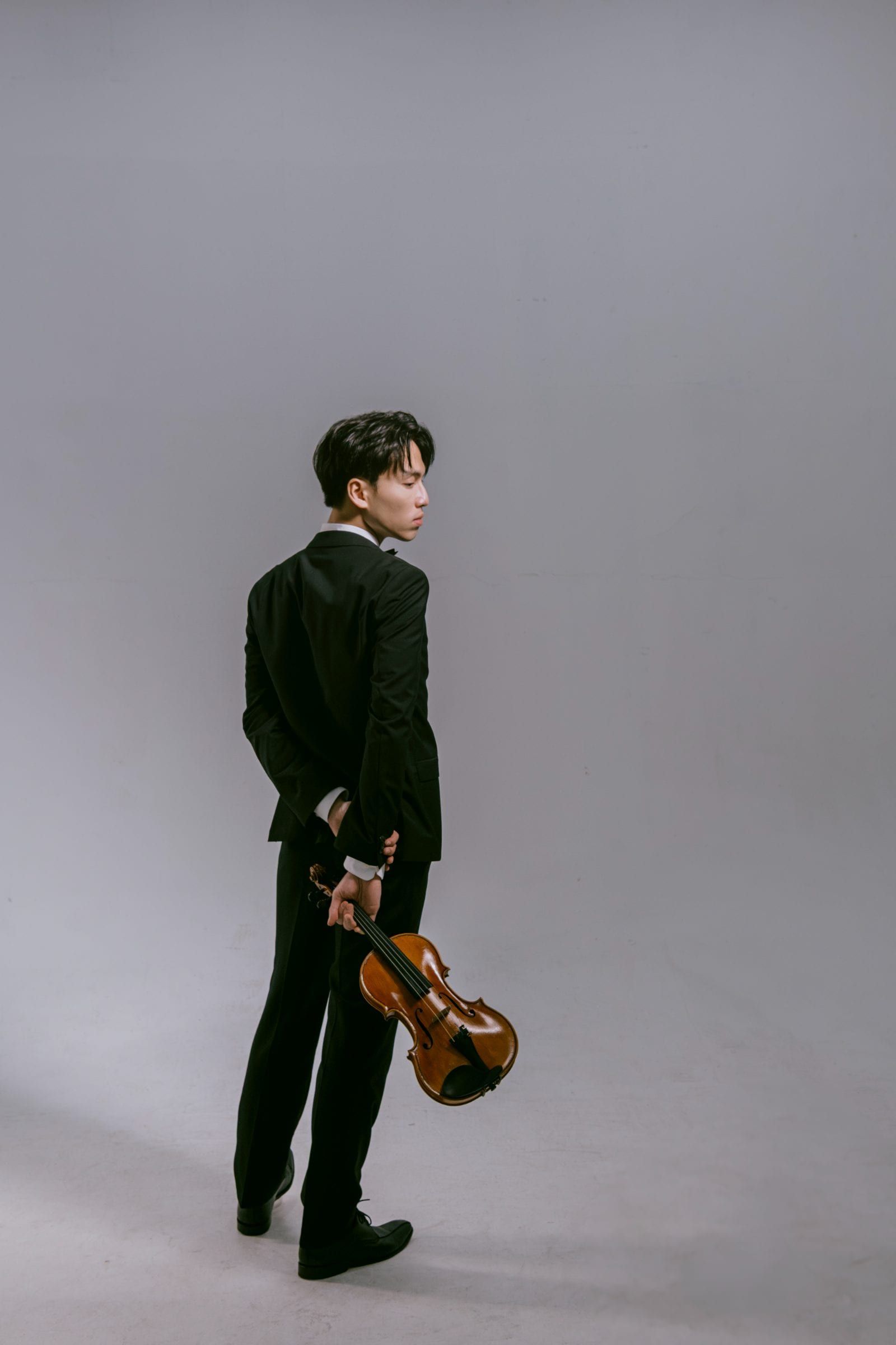 Full-length studio portrait of violinist Trần Lê Quang Tiến with his instrument