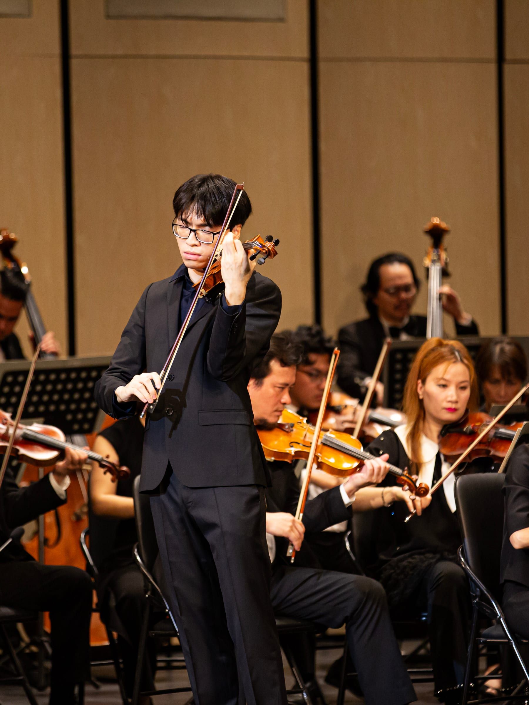 Trần Lê Quang Tiến playing violin during a live recital
