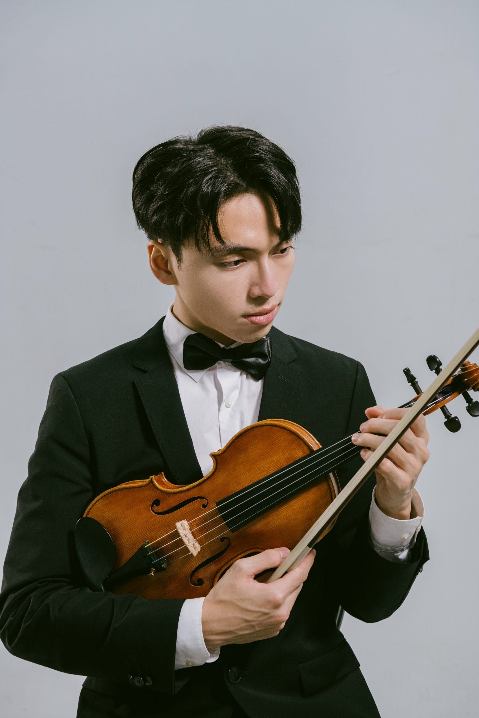 Violinist Trần Lê Quang Tiến in studio, holding bow over the violin